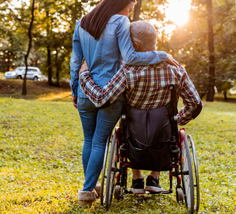 Man in wheelchair holding standing woman
